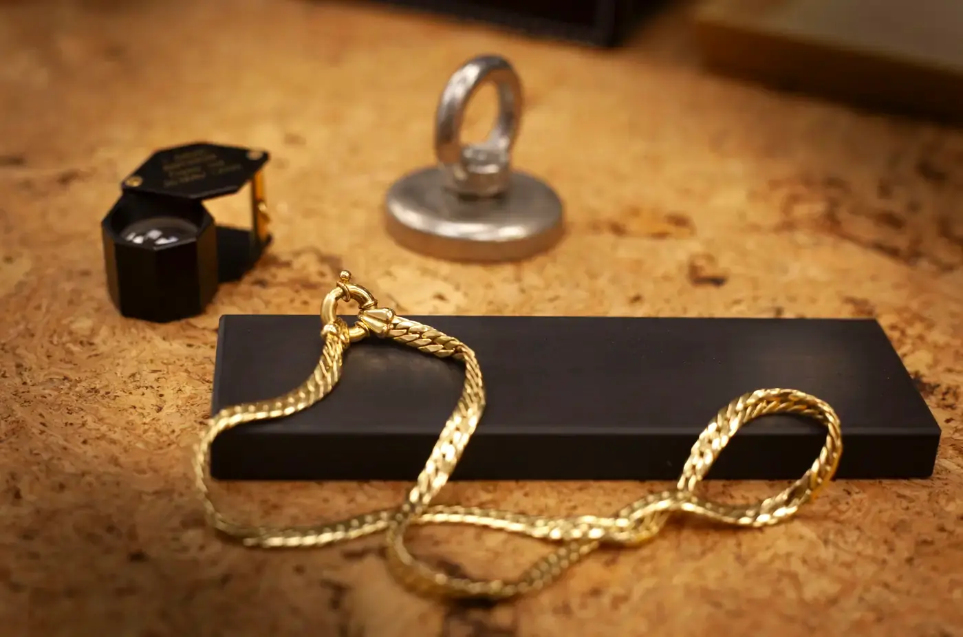 Loupe de bijoutier et chaîne en or sur la pierre de touche